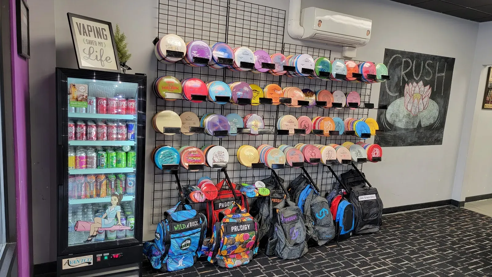 Interior wall with disc golf discs, bags, and a drink cooler.
