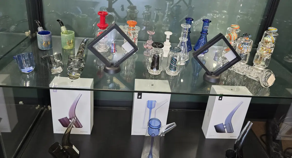 Display case of hand-blown glass pipes, dab rigs, and Puffco Proxy vaporizers.