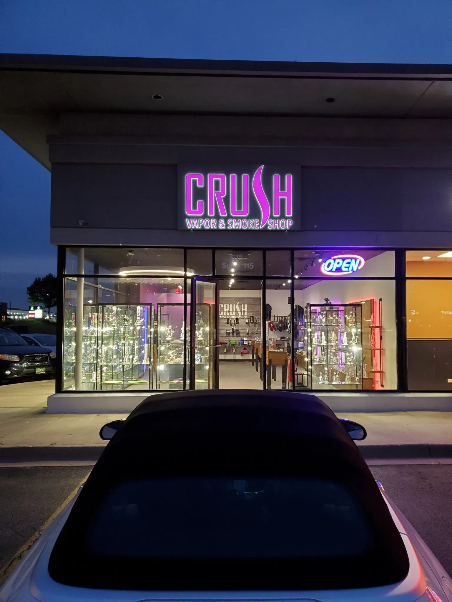 Exterior of Crush Vapor & Smoke Shop with a glowing pink sign.